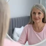 Kobieta po 60 roku życia przeglądająca się w lustrze