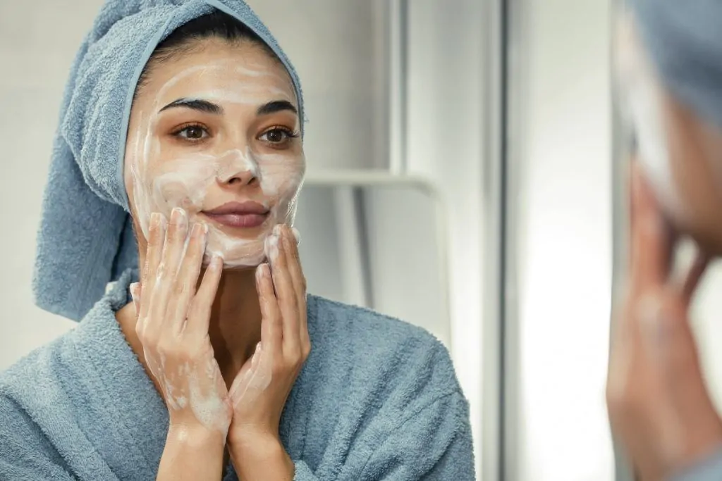 Kobieta przeglądająca się w lustrze podczas pielęgnacji twarzy