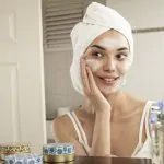 Kobieta nawilżająca skórę twarzy kremem